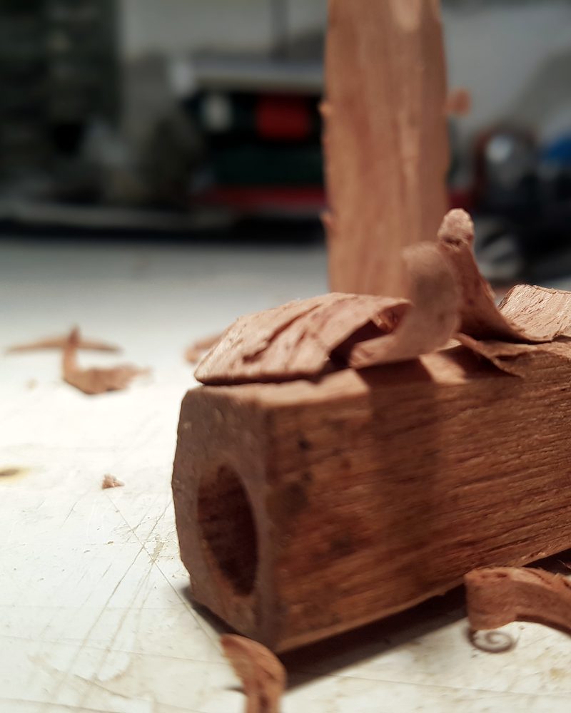 Un blocco di legno rosso forato al centro, tra i trucioli